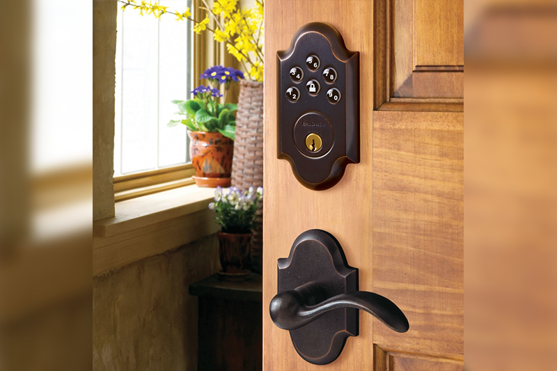 A door with a key pad and a flower pot in the background.