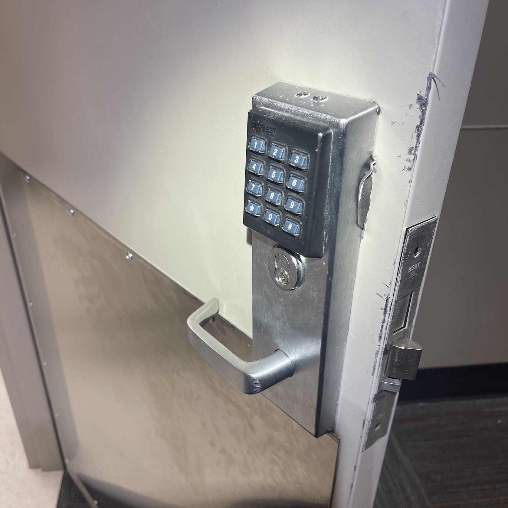 A door with a metal handle and a digital keypad.