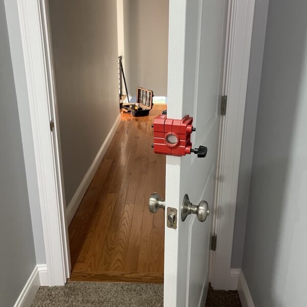 Red door installation tool in hallway.