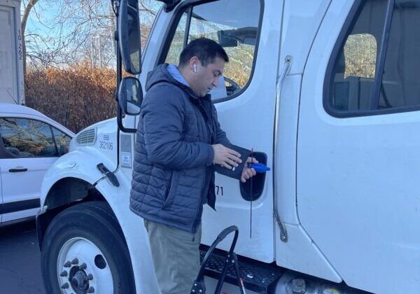 A man standing next to the side of a white truck.